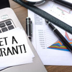 close up of a sticky note that says, get a grant, sitting on an open laptop on an office desk